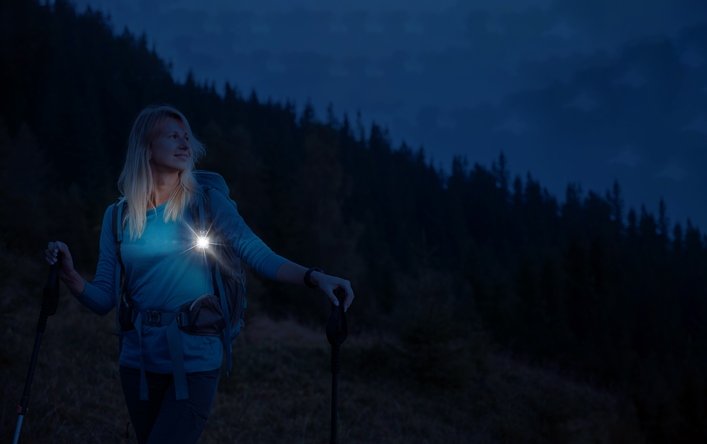 Beautiful woman hiker standing on grassy hill in mountains.